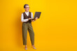 © deagreez - Mature businesswoman smiling with laptop against bright yellow background in professional attire