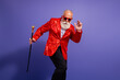 © deagreez - Energetic elderly performer in a red sequined jacket poses with a cane during a vibrant party show against a purple studio backdrop