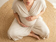 © Jai Izzam - High angle view of faceless pregnant woman sitting on round jute rug doing breathing exercise holding belly