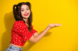 © deagreez - Glamorous young woman with red floral top smiles against yellow background presenting with open hand