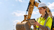 © Vyatcheslav - Female construction engineer with tablet at site. Professional woman in hard hat and safety vest by excavator. Site management and technology concept