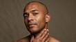 © Vyatcheslav - Close up portrait of a bald man touching his neck. Male skincare and grooming concept. Headshot of a confident african american man on a brown background