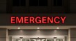 © Khanarhi - Ultra high resolution professional editorial photograph of a modern hospital emergency entrance at night with bold red EMERGENCY sign, clean glass doors, minimal architecture, and pristine quality