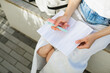 © RooM The Agency - Overhead view of a mid adult woman sitting on a bench with an open notebook and pens in summer