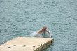 © STOCKEROcr - Man splashing into the water after jumping from a dock in Lake Arenal