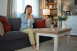 © Jelena - Stressed woman suffering headache pain sitting on sofa