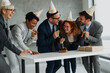 © Novak - Group of happy business colleagues celebrating company anniversary in the office with cake