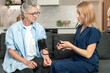 © brizmaker - Medical professional checks blood pressure of elderly patient at home visit