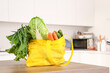© Pixel-Shot - Yellow shopper bag full of fruits and vegetables in kitchen