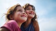 © CreativeInside - Two cheerful young girls gazing joyfully at the bright blue sky outdoors