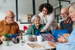 © Halfpoint - Volunteer teaching seniors how to recognize fake news on digital tablet.