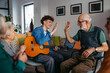 © Halfpoint - Young musician volunteer with guitar giving high five to senior man.