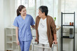 © Ekkasit A Siam - asian female therapist gently placing hand on elderly asian woman’s arm while encouraging movement with walker during rehabilitation session in cozy daylight clinic for senior physical recovery