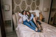 © svetograph - Women Bedroom Photo Shoot Pelican Plush Toy: Two women relaxing on bed, playful pose with stuffed pelican, interior setting.