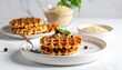 © wahyu - Delicious homemade waffles topped with berries and mint, served on a white plate with a fork and a bowl of ingredients in the background.