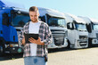 © Serhii - Truck driver checking logistics documentation inspecting fleet of trucks
