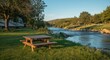 © AkuAku - Camp table placed on grassy river edge within an RV campground