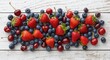 © TheWaterMeloonProjec - Flat lay image of mixed strawberries blueberries and cherries on white wood
