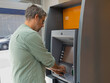 © Nuria - Man interacting with an automated teller machine (ATM), managing personal finances and withdrawing cash from his account