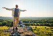 © baranq - Young man with outstretched arms standing on top of a rock in Jura Poland enjoying summer day