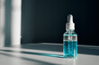 © colnihko - Dropper bottle containing blue liquid two-phase skincare serum on table with harsh shadow