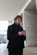 © KONSTANTIN SHISHKIN - Young man using smartphone communicating online in urban setting