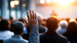 © Curioso.Photography - Man raising his hand in a crowded auditorium during a conference symbolizing participation, learning, and engagement.