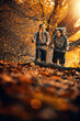 © ivanko80 - Two people hike through autumn forest with bright orange leaves on the ground in the afternoon light