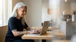 © jockermax3d - Mature woman typing on laptop in a cafe
