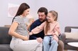 © New Africa - Pregnant woman, her husband and daughter on sofa at home