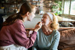 © Geber86 - Granddaughter applying facial mask to grandmother in living room