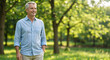 © Vyatcheslav - Handsome middle aged man smiling in a green park. Happy mature male standing outdoors with hands in pockets. Casual lifestyle portrait with copy space