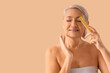 © Pixel-Shot - Mature woman with collagen stick on beige background