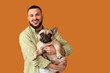© Pixel-Shot - Handsome young happy man with cute French bulldog on yellow background