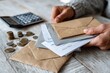 © id512 - Stressed middle aged person organizing household expenses and bills at home table, financial anxiety concept. Adult hands counting coins and checking budget notes with calculator, inflation and cost