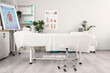 © Pixel-Shot - Interior of massage therapist's office with couch, shelving unit and poster on flipchart in modern medical centre