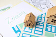 © Pixel-Shot - Clipboard with word ZONING and house figures on plan, closeup