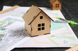 © Pixel-Shot - House figure with zoning plan and city map on dark background, closeup