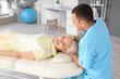© Pixel-Shot - Male physiotherapist working with mature woman on couch in rehabilitation center