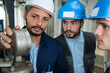 © auremar - three male workers inspecting gauge on factory machinery