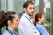 © StockMe - Healthcare professionals standing together, including a doctor looking seriously, representing healthcare professionals and frontline workers