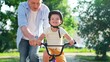 © Victoriia - Child wearing helmet father learning to ride bike outdoors in summer. Smiling boy cyclist plays with dad city park. Family weekend. Dad teaches his young son to ride bike in park. Happy family, nature
