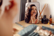 © Vlad - Sexy brunette young woman applying lipstick on lips in front of mirror at home while doing everyday makeup. Beauty, cosmetics concept