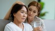 © Mary - Young woman comforting elderly woman with glass of water indoors