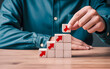 © Sefat - Person placing wooden block with red arrow on top of stacked blocks on a table