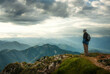 © Smileus - Hiker enjoying the majestic and moody view on a mountain top. The Austrian and Slovenian Alps with dramatic clouds.