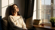 © Prabhash - Young woman relaxing by a window enjoying warm sunlight and peaceful moment at home