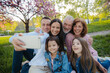 © Halfpoint - Three generation family sitting outside in spring nature, taking selfie.