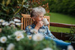 © Halfpoint - Senior woman with coffee sitting on terrace, resting after gardening.