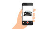 © pookie - Hand holding smartphone to photograph a damaged black car, initiating an auto insurance claim process.
